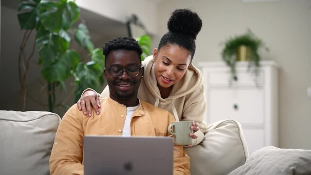 Diverse couple using laptop together at home - Powered by Adobe
