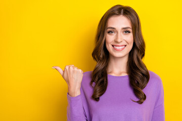 Photo of adorable cute lady wear violet sweater pointing thumb empty space isolated yellow color background