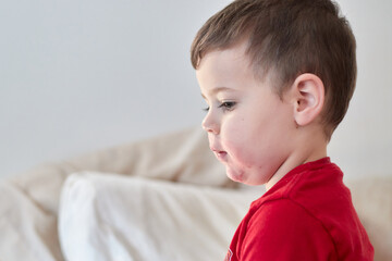 cute boy watching tv on the bed with face in strawberry juice