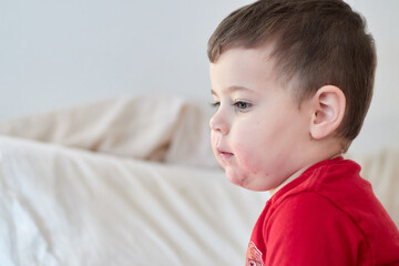 cute boy watching tv on the bed with face in strawberry juice