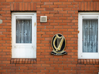 Irish harp emblem and sign Eire on a red brick wall of a building. National symbol of Ireland....