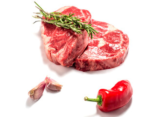 Fresh premium rib eye steak on white isolated background with green herb and garlic clove and red pepper. Premium beef cut. Top quality meat.