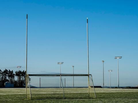 Irish sport training ground with tall goal posts for camogie, Gaelic football and rugby on a cold winter day. Frost on the green grass.