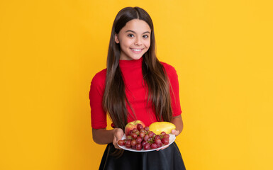 child smile hold fresh fruit plate on yellow background