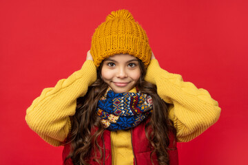 happy teen girl in knitted winter hat and scarf on red background, cold season