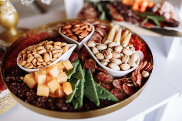 Assorted appetizers table with different antipasti, variations of nuts, pistachios, almonds, peanuts, charcuterie, snacks, cheese. Finger food for buffet party. Traditional french or italian entries.