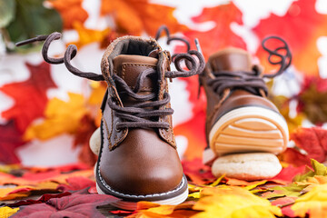 leather, children's boots for a brown boy, against the background of autumn leaves. Photo in motion. Space for text.