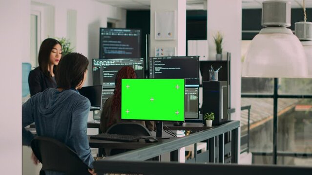 Team of programmers working on source code with greenscreen monitor in cloud computing office. App developers checking isolated chromakey display with copyspace and html script. Tripod shot.