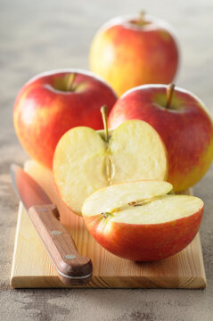 Close-up of Red Apples on Cutting Board with Knife, One Cut in Half