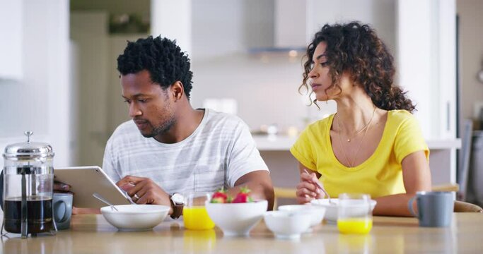 Couple, tablet and breakfast with a man and woman eating together while browsing the internet online. Distracted, digital tablet and boyfriend avoid girlfriend during morning meal in the kitchen
