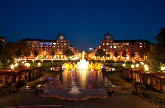 View of Water Fountain at night, with Arcade Buildings in background at Freidrichsplatz, Mannheim, Germany