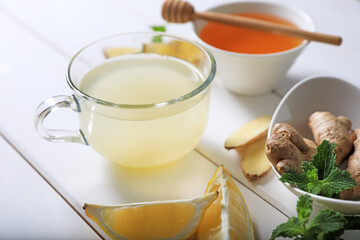 Delicious ginger tea and ingredients on white wooden table