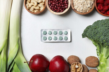 Blisters of pills and foodstuff on white table, flat lay. Prebiotic supplements