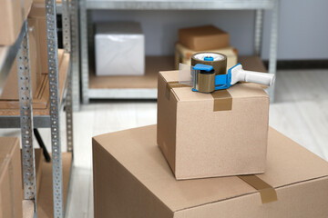 Adhesive tape dispenser on cardboard box indoors. Space for text