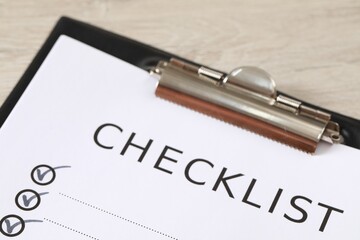 Obraz premium Clipboard with inscription Checklist on wooden table, closeup