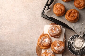 Delicious profiteroles with powdered sugar on grey table, flat lay. Space for text