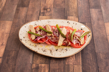 A traditional Spanish tuna belly salad with plenty of red onion, tomato slices, lots of olive oil and salt and wild asparagus