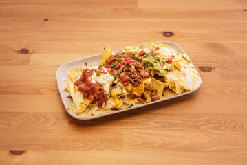 A recipe tray of Mexican corn nachos with fresh cheese, guacamoles, chile con frijoles, and pico de gallo