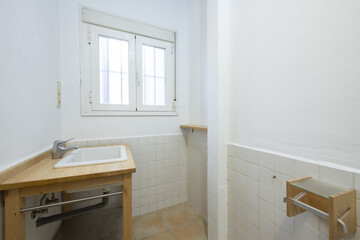 Toilet with white porcelain sink integrated into a wooden cabinet without doors and a white aluminum window