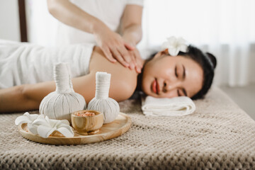 Obraz na płótnie Canvas Relaxed pretty asian young woman enjoying remedial body massage done by professional masseur in spa room