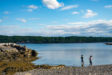 Fototapeta na wymiar A couple walking on a beach in Maine in the summertime