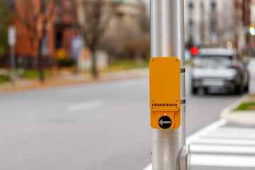 Yellow pedestrian push button sign on traffic signal pole at crossroad in street in Canada