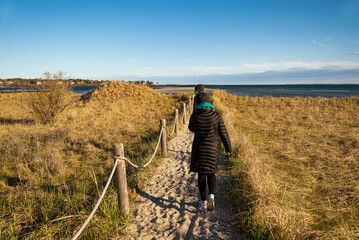 Fototapeta na wymiar Two women walking on a dirt path at a beach in Maine in the wintertime