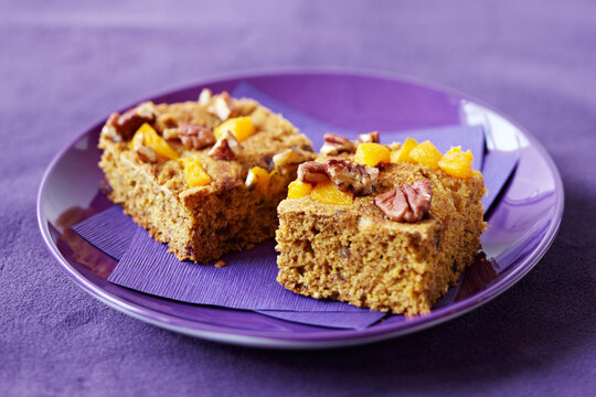 Pecan peach cake squares on a purple plate with purple napkin, studio shot on purple background