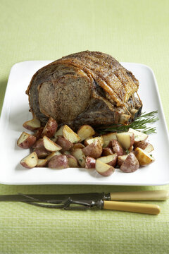 Prime rib roast beef with baby red potatoes on a green background