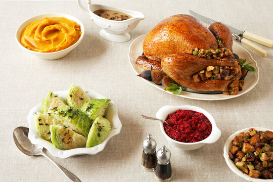 Thanksgving turkey with side dishes on a linen table cloth