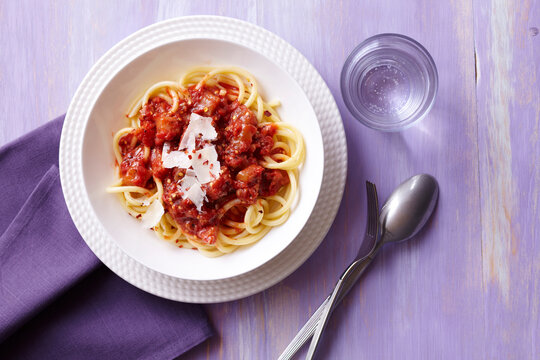 Bucatini with tomato sauce and cheese on a purple background