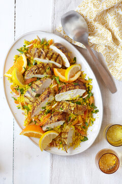 Platter of sliced chicken breast on couscous with orange and lemon slices