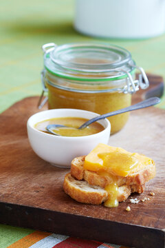 Honey mustard on bread with chesse on wooden cutting board with jar and spoon in background