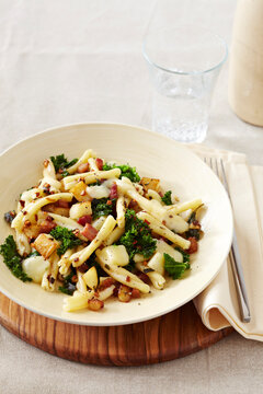 Gemelli pasta with bacon bits, potatoes, garlic and kale, and cheese in a bowl