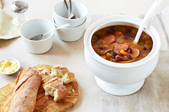 Soup tureen of Hungarian Bean Soup with crusty bread on the side on a linen tablecloth
