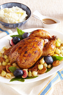 Honey roasted chicken with figs and onions served on a platter with side dishes of mashed potatoes and gravy