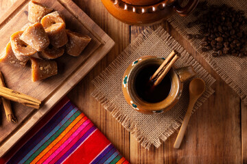 Authentic homemade mexican coffee (cafe de olla) served in traditional handmade clay mug (Jarrito de barro) on rustic wooden table.