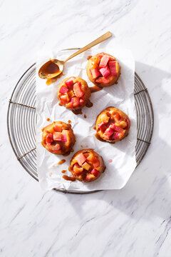 Rhubarb mini cakes with caramel sauce on a cooling rack on white marble