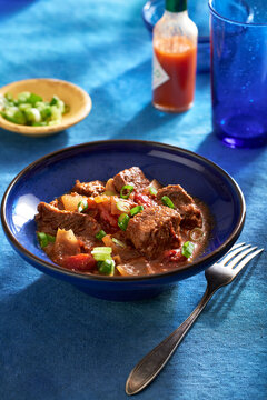 Texas style chili in a blue bowl with a fork on a blue background