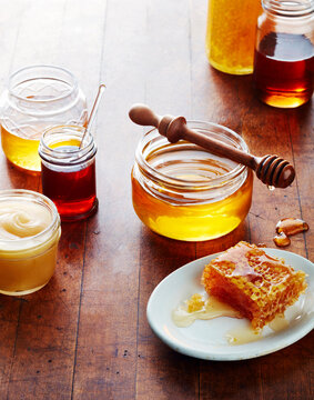 Still life of honey jars with honeycomb and wooden, honey dipper