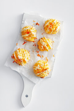 Orange macaroons with white chocolate drizzle on a cutting board