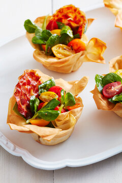 Bacon and tomato phyllo cups on a white platter