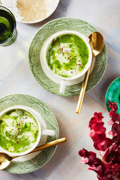 Watercress soup in tea cups with spoons and flowers