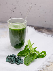 spirulina smoothie with a few leafs on a white background