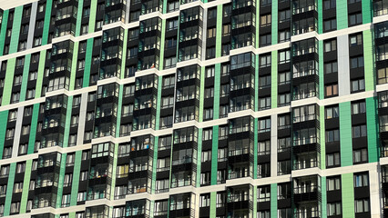 Fototapeta na wymiar Facade of the building in green and lettuce colors, geometric patterns from windows and balconies, colored wall of a modern multistory apartment building, abstract texture of the house facade