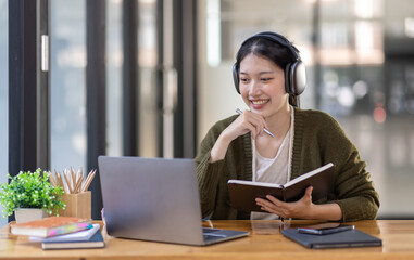 Young adult happy smiling Hispanic Asian girl student wearing headphones talking on online chat meeting using laptop in university campus or at virtual office. College female student learning remotely