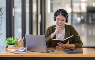 Young adult happy smiling Hispanic Asian girl student wearing headphones talking on online chat meeting using laptop in university campus or at virtual office. College female student learning remotely