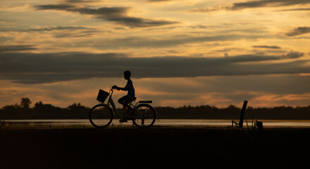 Obraz premium Little boy riding bicycles in the early light of the day as the sun shines
