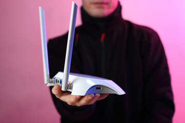 a person holding a white router with two antennas - 555805344