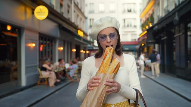 Smiling girl eating french baguette from a bakery